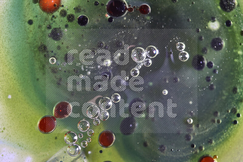 Close-ups of abstract red, green and blue watercolor drops on oil Surface on green background