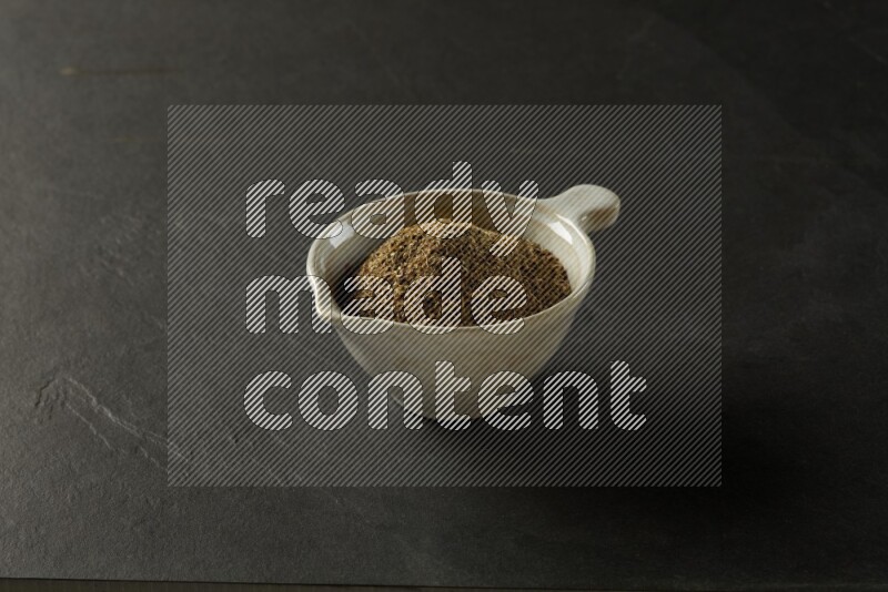 white ceramic round sauce bowl filled with herbs on grey textured countertop