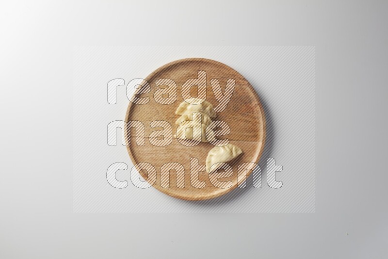 Four Sambosas on a wooden round plate on a white background