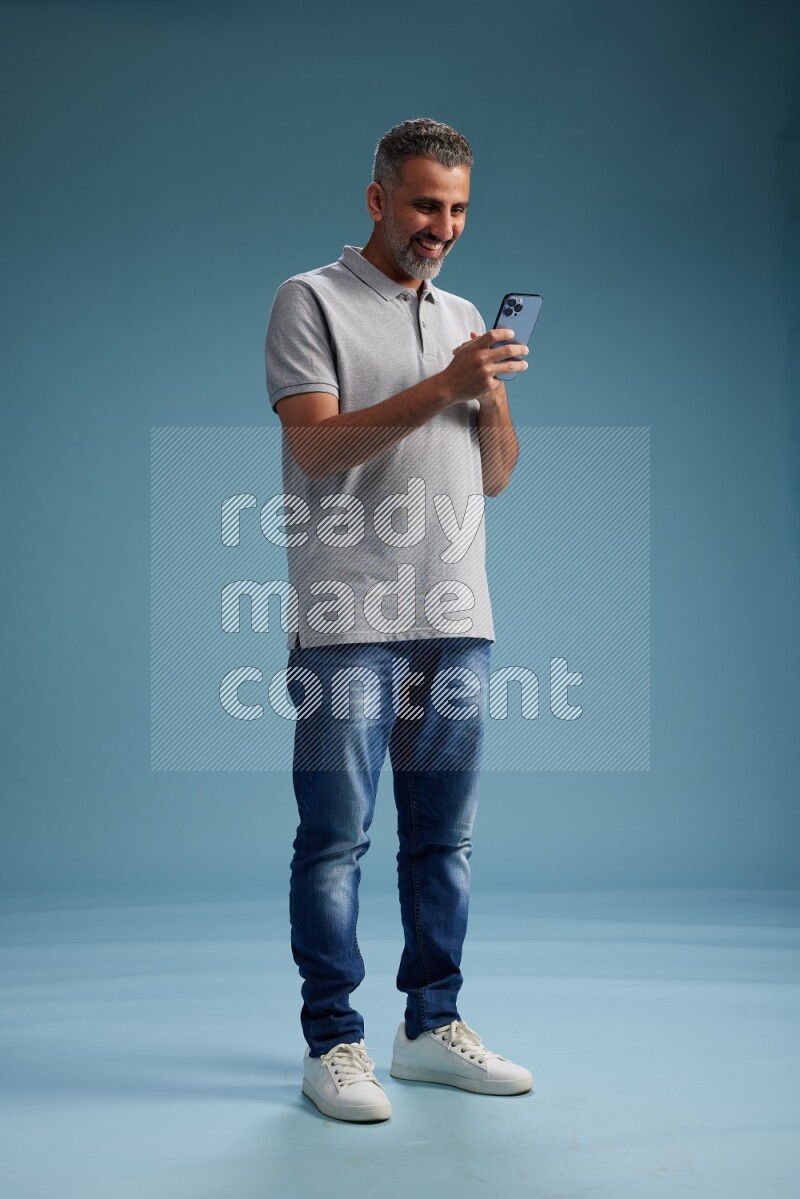 Man Standing texting on phone on blue background