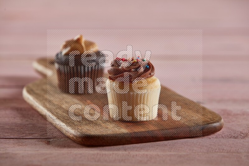 Vanilla mini cupcake topped with chocolate cream on a wooden board