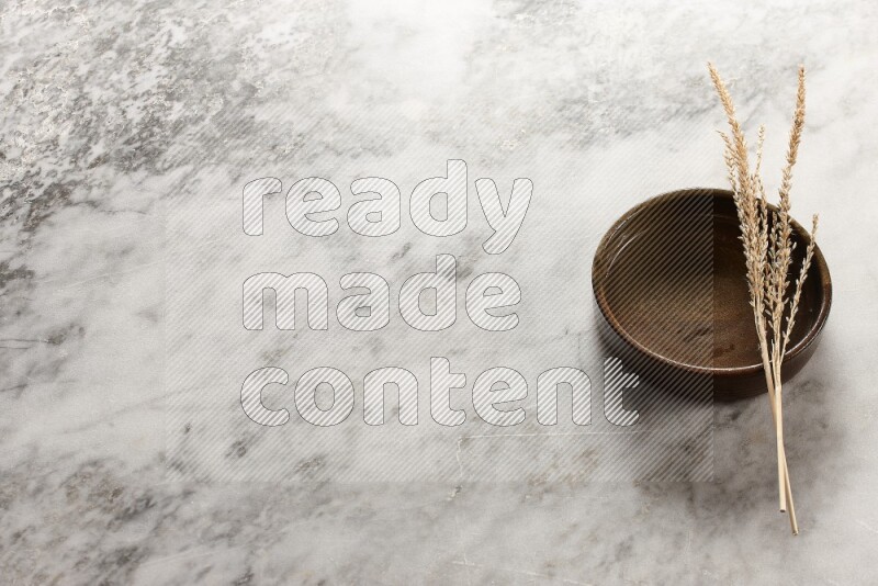 Wheat stalks on multicolored pottery oven plate on grey marble background