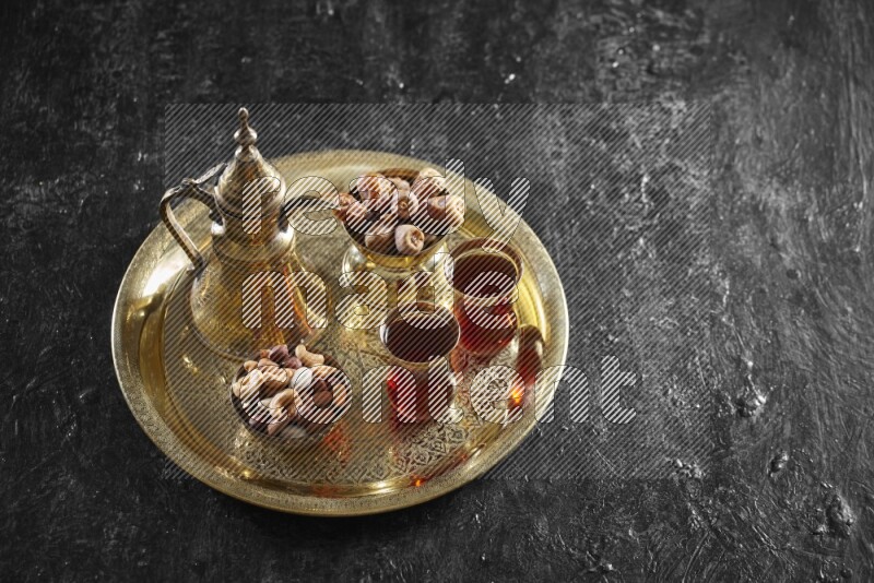 Nuts with dates and a drink on a metal tray in a dark setup