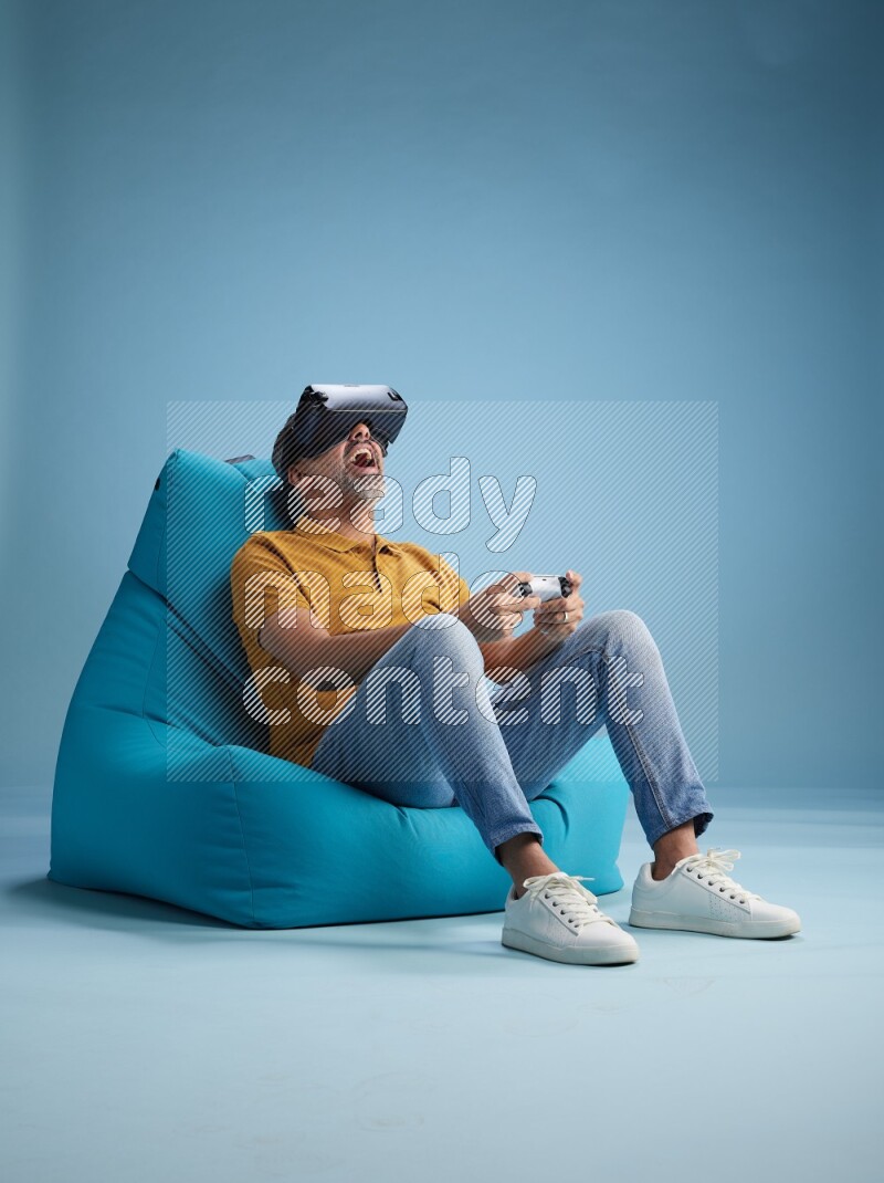 A man sitting on a blue beanbag and gaming with VR