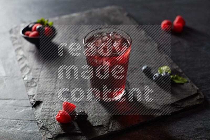 A glass of mixed berries juice on black background
