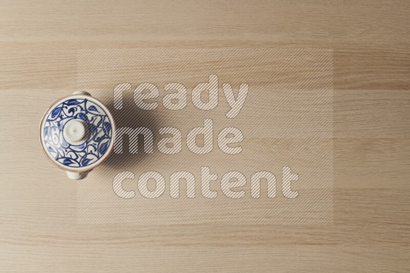 A multicolored pottery pot on light wooden background