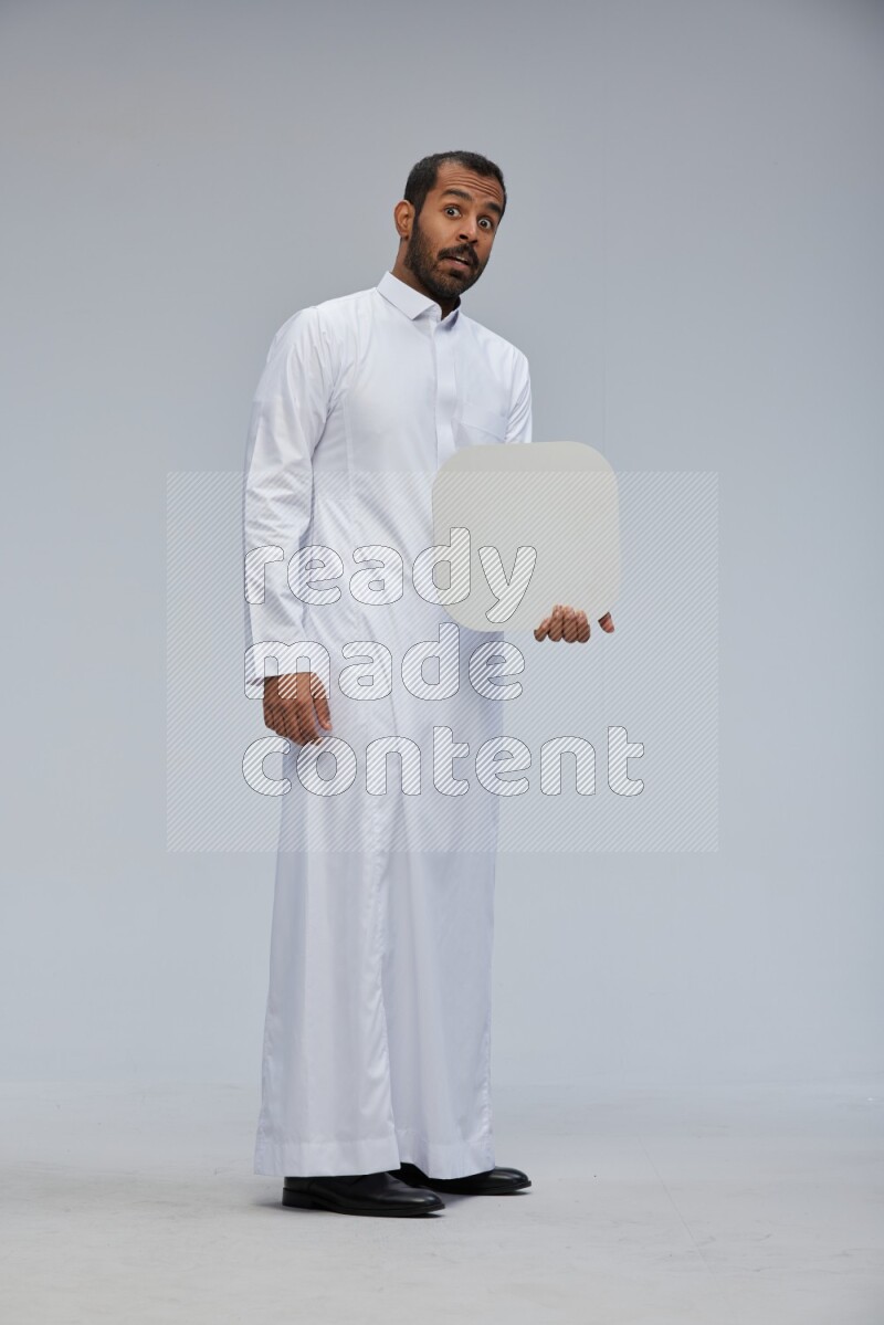Saudi man wearing Thob standing holding social media sign on Gray background
