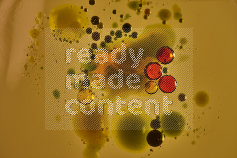 Close-ups of abstract red, blue and yellow watercolor drops on oil Surface on yellow background