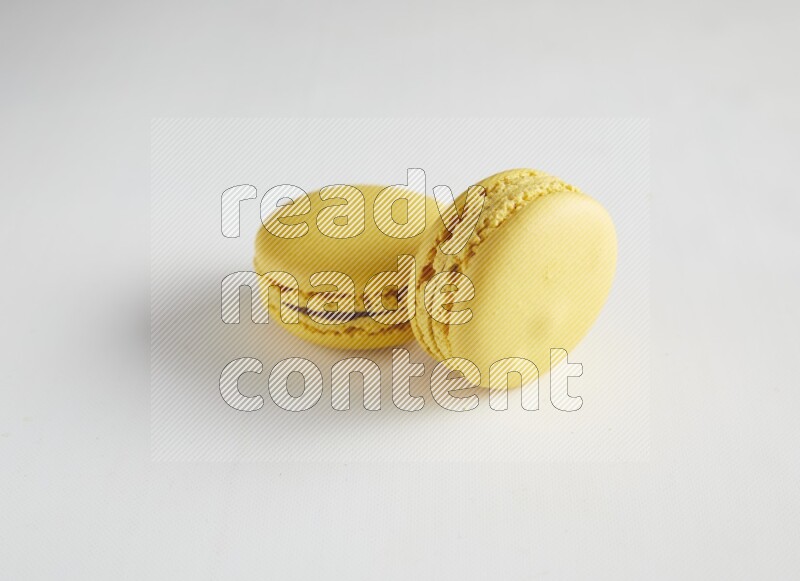 45º Shot of two Yellow Lemon macarons on white background
