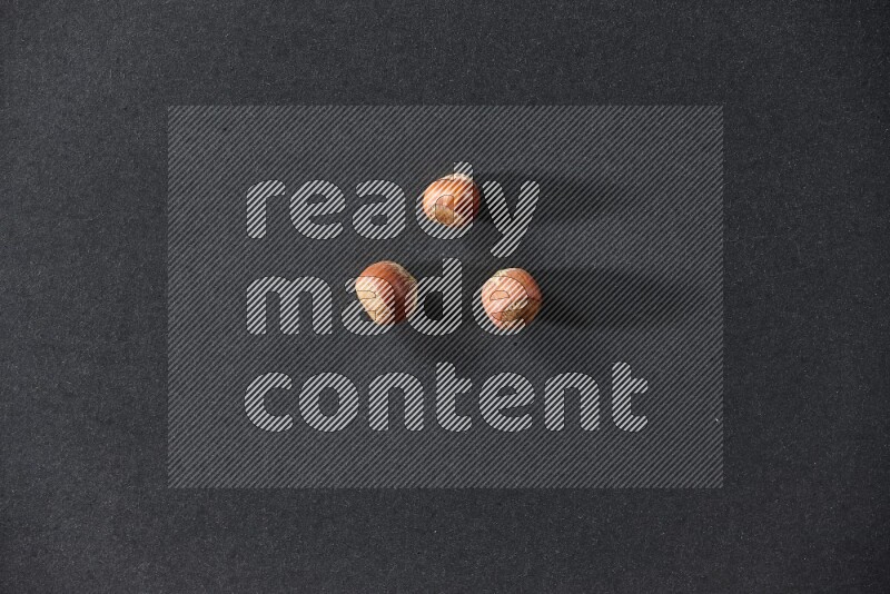 3 hazelnuts on a black background in different angles