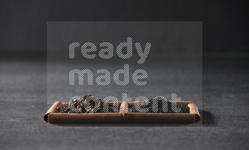 مربعان من أعواد القرفة ممتلئان بحبة البركة السوداء والقرنفل علي خلفية سوداء