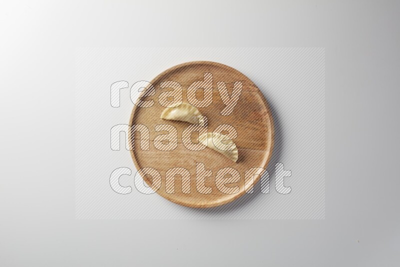 Two Sambosas on a wooden round plate on a white background