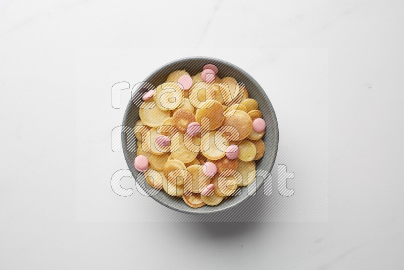 Top-view shot of pink chocolate chips cereal pancakes in a round bowl on white background