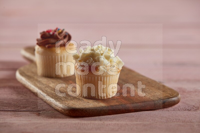 Vanilla mini cupcake topped with white chocolate curls on a wooden board