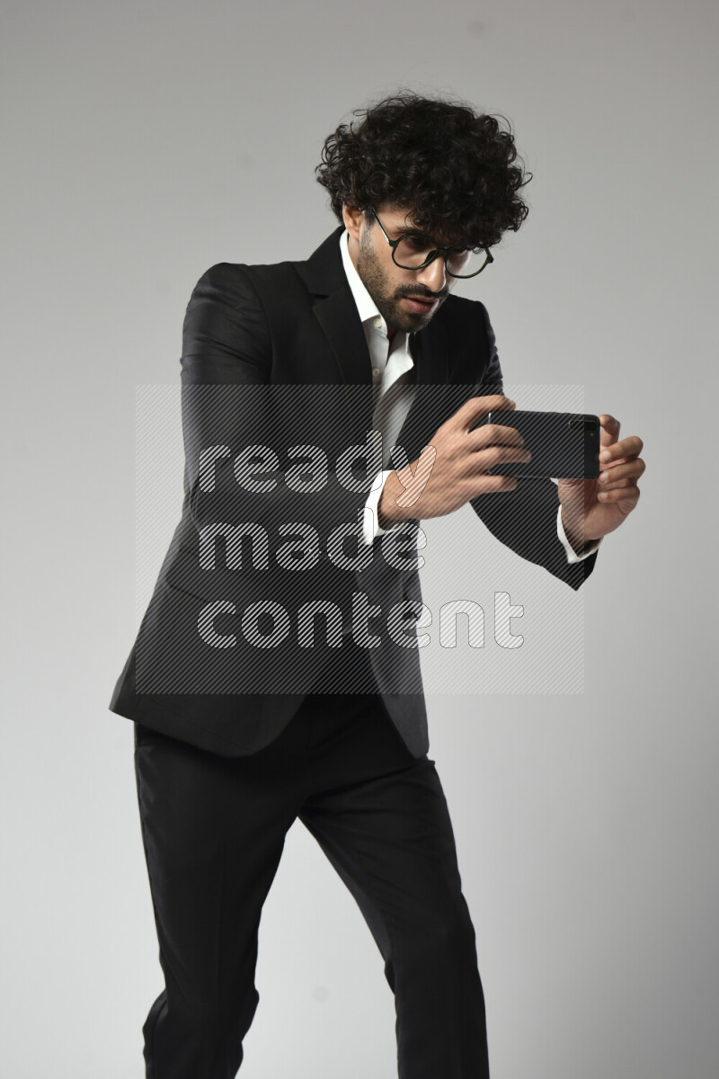 A man wearing formal standing and shooting with his phone on white background