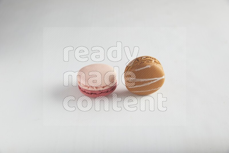 45º Shot of of two assorted Brown Irish Cream, and Pink Litchi Raspberry macarons on white background