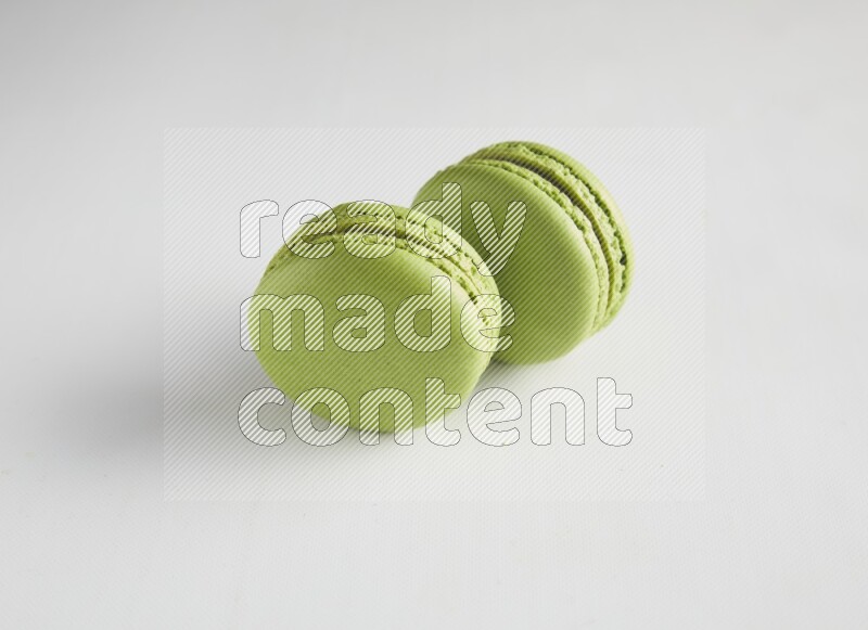 45º Shot of two Green Pistachio macarons on white background