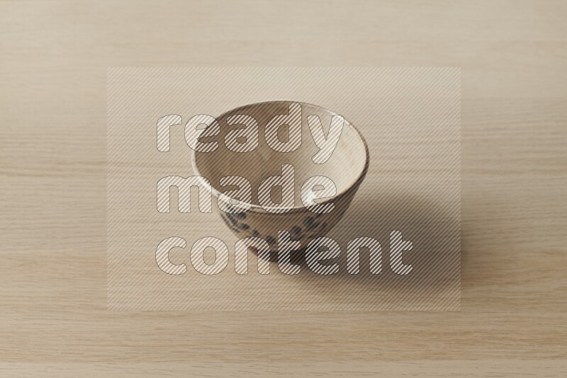 A decorative pottery bowl on light wooden background