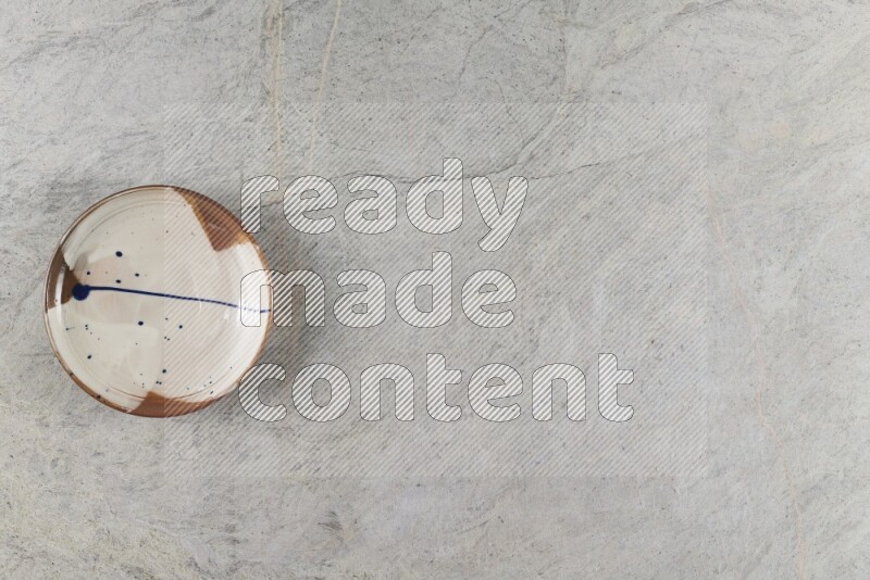 A multicolored pottery plate on grey marble background