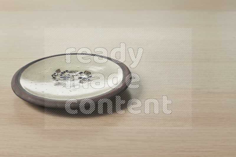 A decorative pottery plate on light wooden background