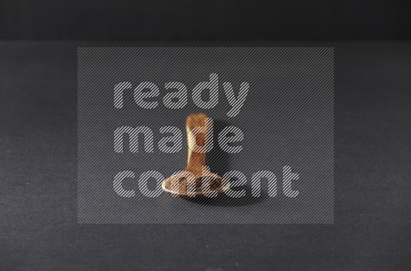 بودرة القرنفل في ملعقة خشبية علي خلفية سوداء