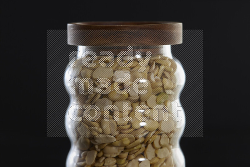 Crushed beans in a glass jar on black background