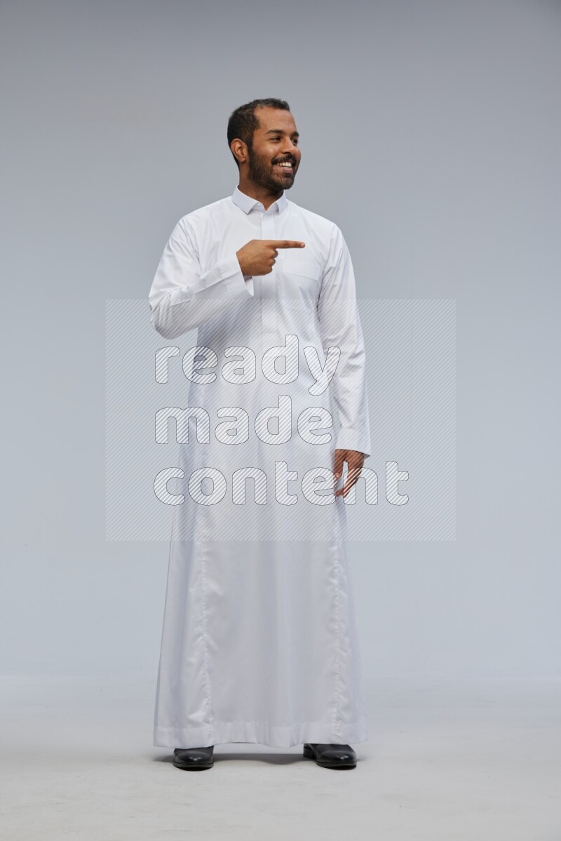 Saudi man Wearing Thob standing interacting with the camera on Gray background