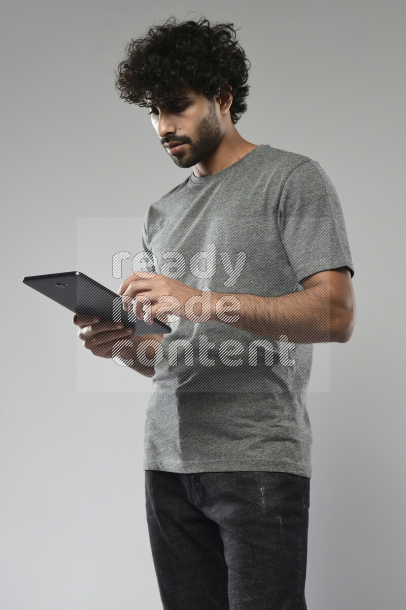 A man wearing casual standing and browsing on a tablet on white background