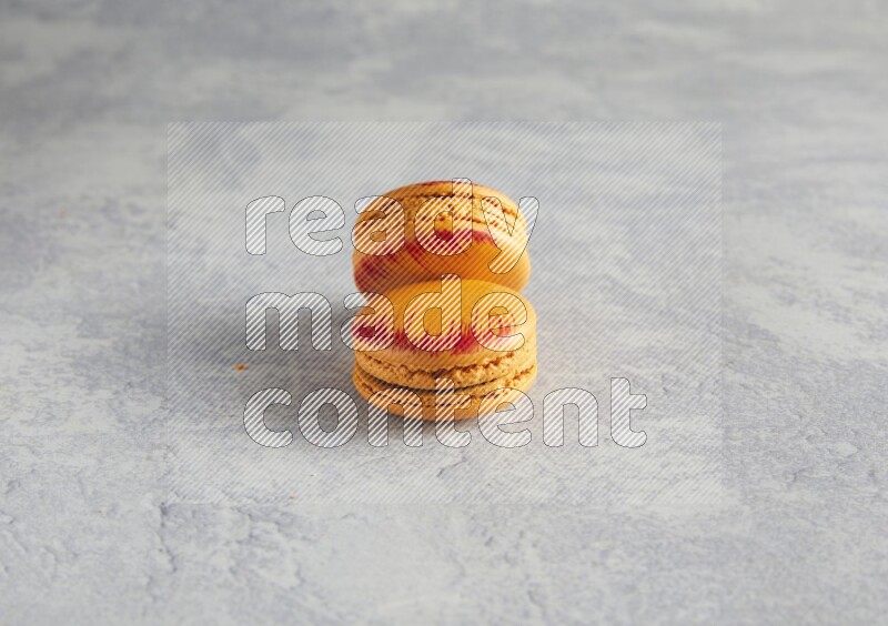 45º Shot of two orange Exotic macarons on white  marble background