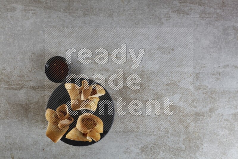 wonton cups with soy sauce ramkin on circle slate on grey textured counter top