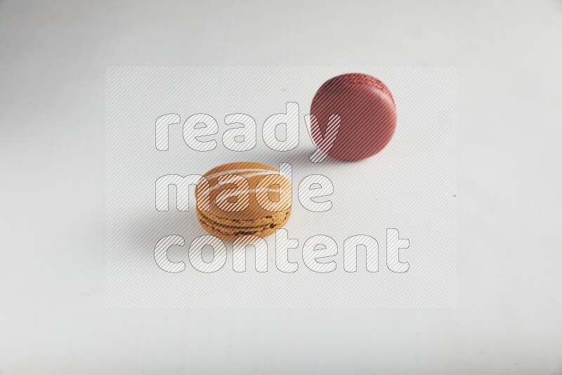 45º Shot of of two assorted Brown Irish Cream, and Red Velvet macarons on white background