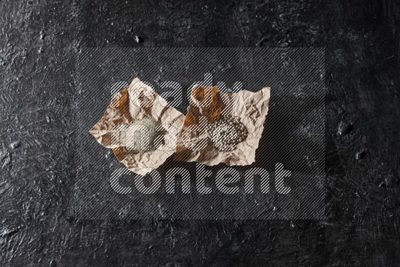 حبات ومسحوق الفلفل الأبيض في ورقتين على أرضية سوداء