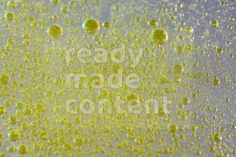 Close-ups of abstract yellow watercolor drops on oil Surface on white background