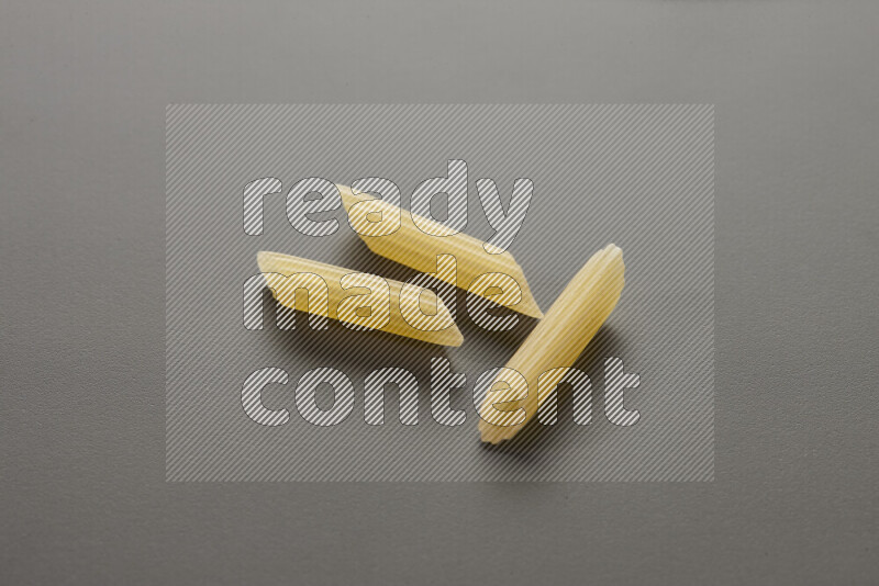Mini penne pasta on grey background