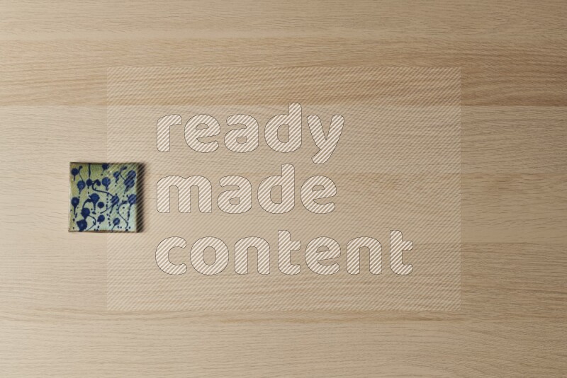 A decorative pottery coaster on light wooden background