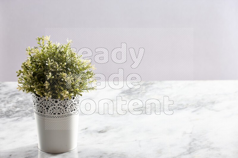 Artificial plant in white decorative pot on grey marble background