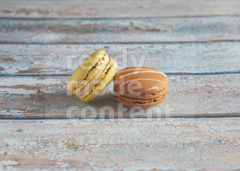 45º Shot of of two assorted Brown Irish Cream, and Yellow Lime macarons on light blue background