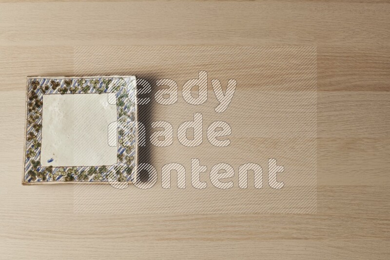 A decorative pottery plate on light wooden background