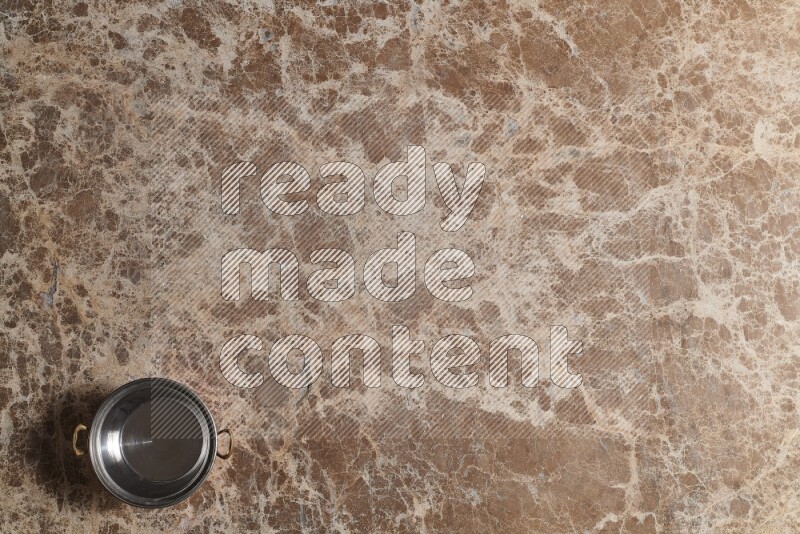 A small copper pot on beige marble background
