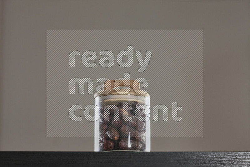 Dates in a glass jar on black background