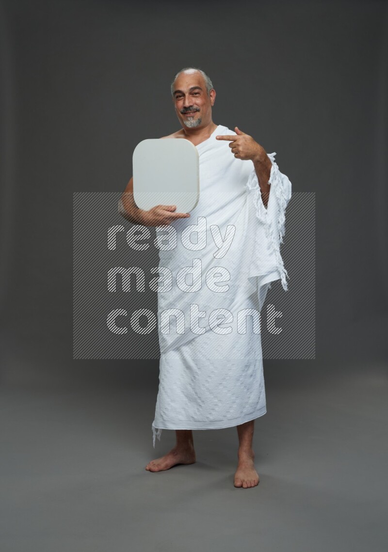 A man wearing Ehram Standing holding social media sign on gray background