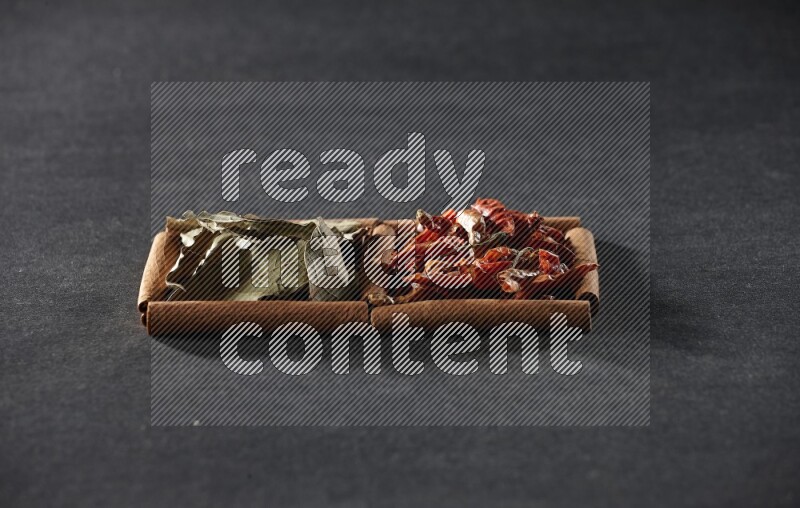 مربعان من أعواد القرفة ممتلئان بالفلفل الحار المجفف وأوراق الغار علي خلفية سوداء