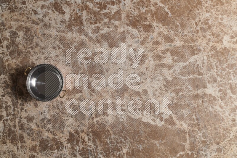 A small copper pot on beige marble background