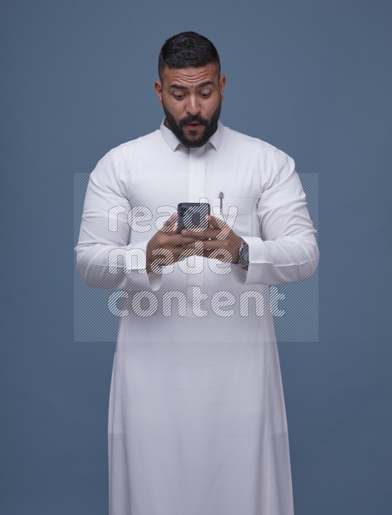 A man Texting on Blue Background wearing Saudi Thob