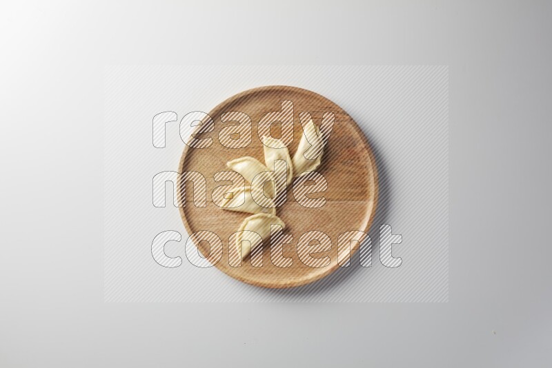 Five Sambosas on a wooden round plate on a white background