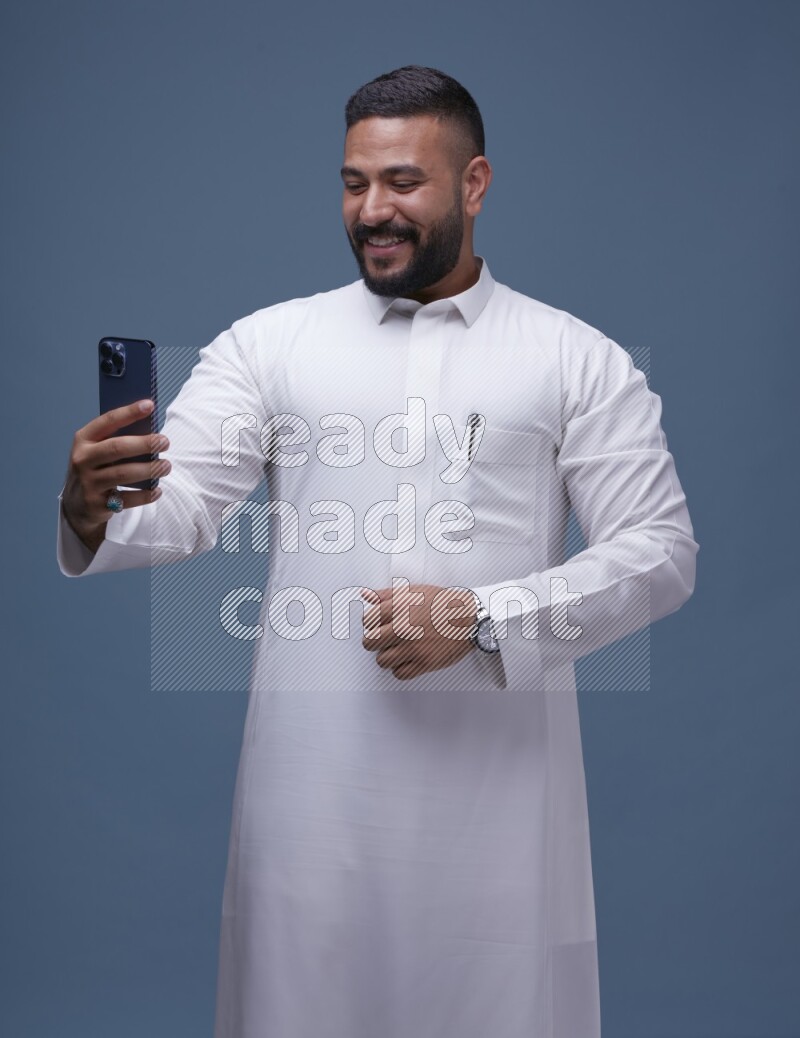 A Saudi man Taking A Selfie on Blue Background wearing Saudi Thob