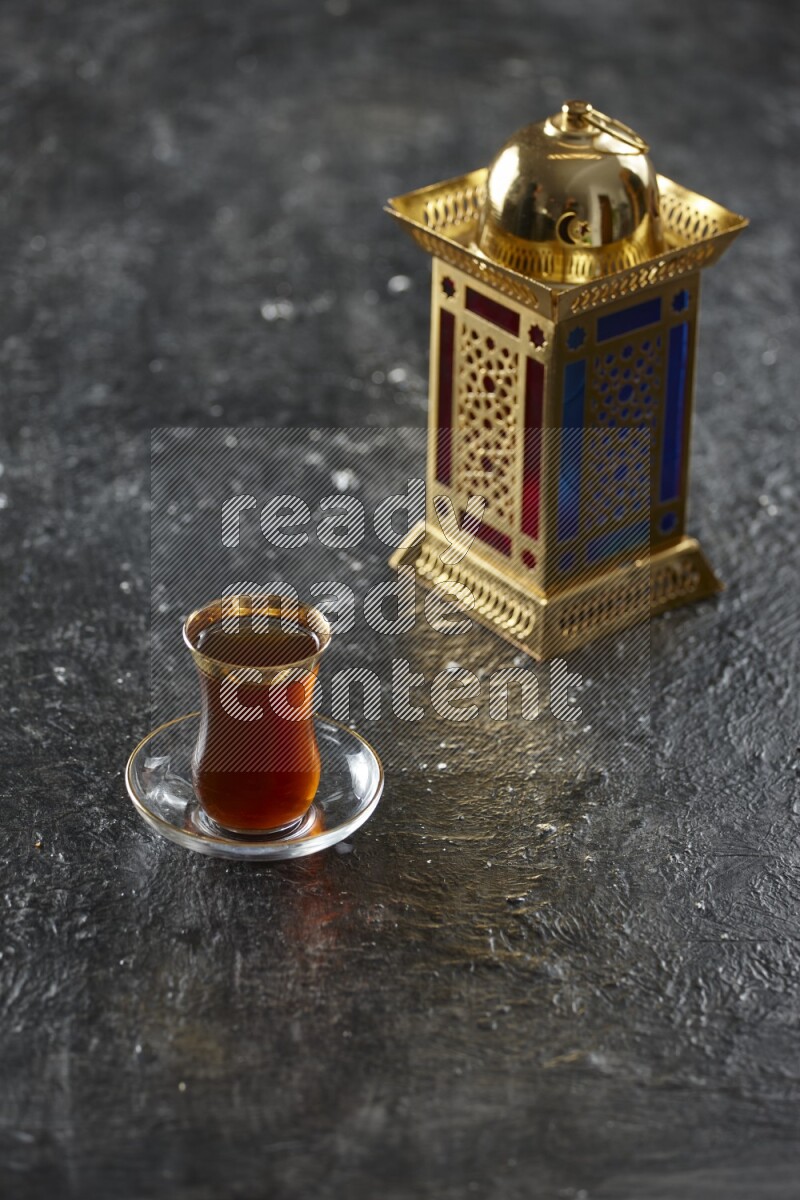 A golden lantern with different drinks, dates, nuts, prayer beads and quran on textured black background