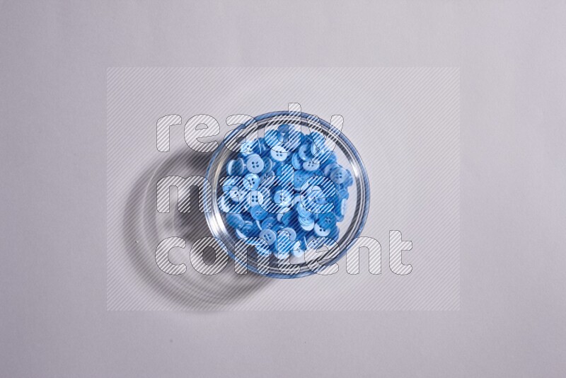 Colored buttons in a glass bowl on grey background
