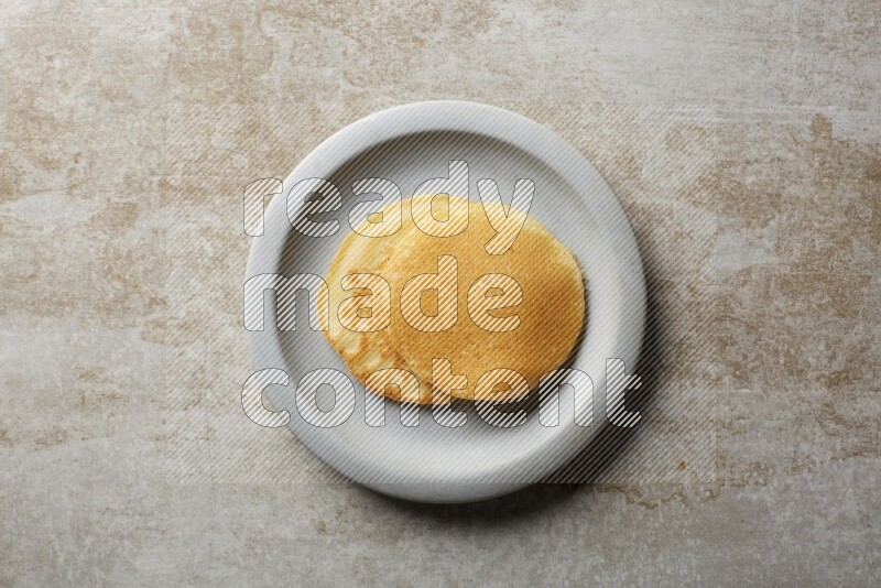 Two stacked plain pancakes in a grey plate on beige background