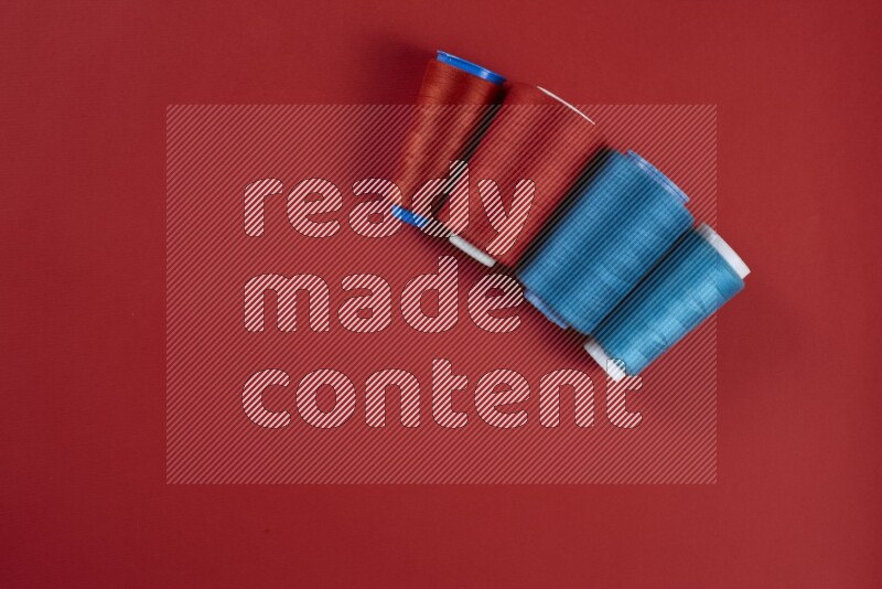 A blue and red collection of sewing and tailoring tools arranged on a red background